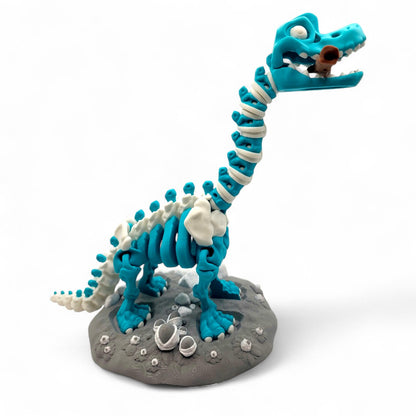 Rear view of the articulated tail and spiked vertebrae, with rocky base and embedded fossil elements in white PLA.